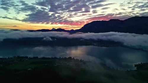 Panoramic view of low level clouds hanging over lake, mountain in the background and sky at sunset