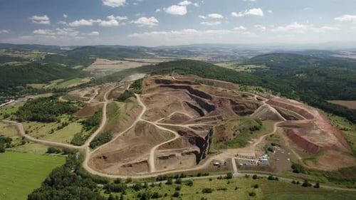 Aerial approach with the tilt-down camera move to the hilltop open-pit melaphyr mining quarry