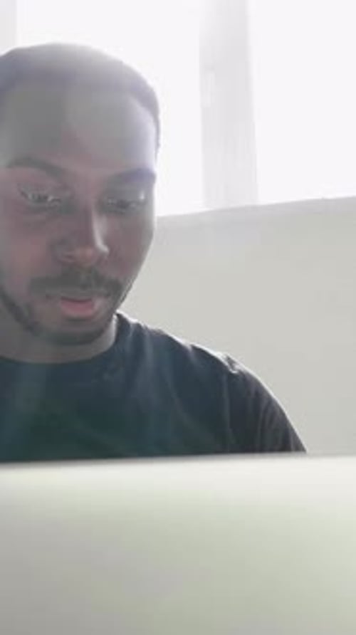 Jeune homme concentré engagé dans le travail sur un ordinateur portable avec un soleil éclatant illuminant la scène