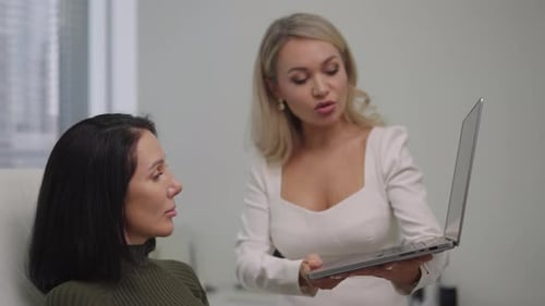 Cosmetologist Consulting Client Discussing Skin Treatment Plan During Beauty Clinic Appointment