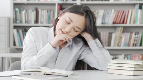 Exhausted Female Student Dozing Off While Studying in the Library