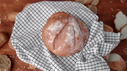 Closeup View of Fresh Baked Rye Bread on Checked Linen Towel on Table of Bakery Rotating Top View