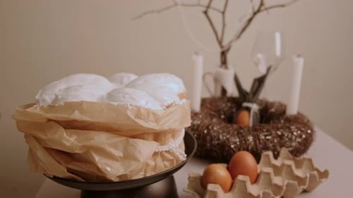 Ostertisch mit Kucheneiern und einem geschmückten Kranz mit brennenden Kerzen nähert sich langsam der Kamera.