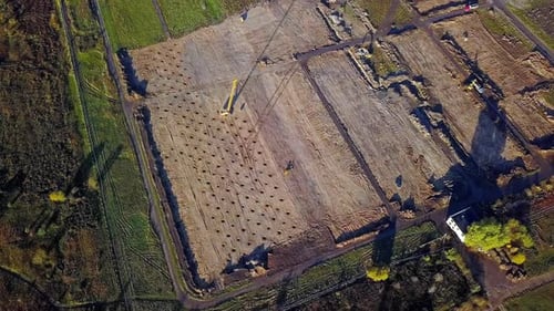 Zumbido aéreo, toma de ángulo alto de una máquina de compactación y camiones para compactar tierra, ocupado trabajando en el suelo