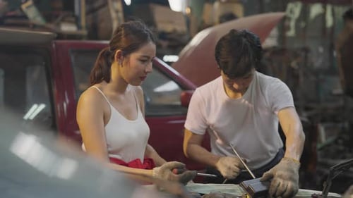 Asian mechanic man help to teach co-worker woman to fix problem of machine in front part of car