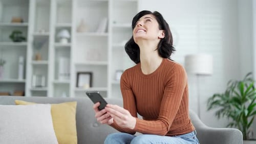 Woman Celebrating Success on Mobile Phone at Home