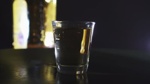 Shot Glass of Clear Alcohol on Black Table