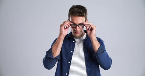 Gesicht, Lächeln und Brille mit einem jungen Mann im Studio isoliert auf grauem Hintergrund zum Entspannen