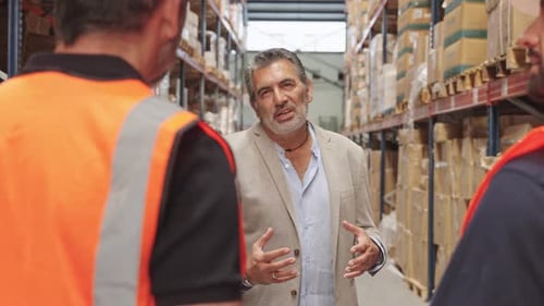 Mature Warehouse Manager Instructing His Team of Workers