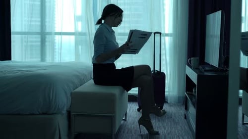 Young businesswoman analyzes financial data in luxurious hotel room with smartphone