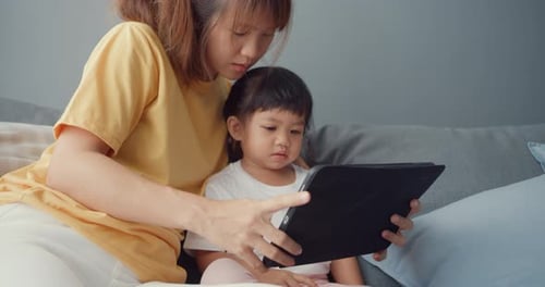Asia family mom and cute kid using digital tablet interest cartoon and watch movie having fun relax.