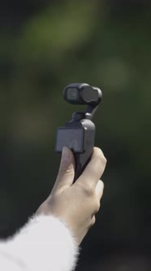 Hand Holding a Compact Gimbal Camera Outdoors