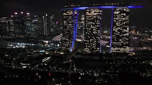 Fly over Supertree Grove towards Marina Bay Sands in Singapore at night