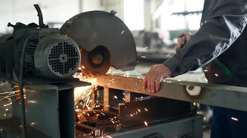 Using cutting machine. A man grinds a metal structure at a factory
