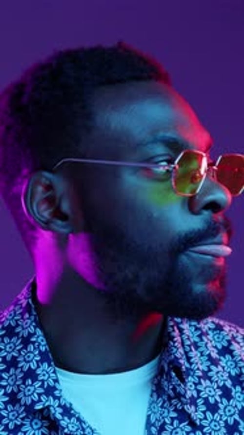 A Stylish Man Wearing Sunglasses Surrounded By Vibrant and Colorful Lighting Effects