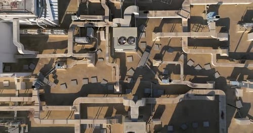 Industrial building rooftops with vents and pipes lined across, Top down view