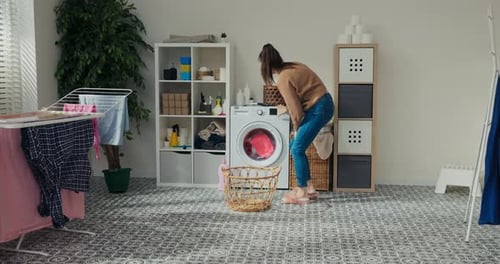Woman Loads Washing Machine in Bright Laundry Room