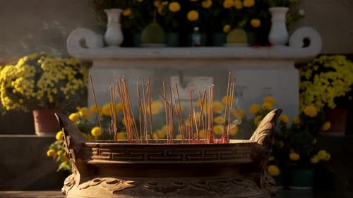 Smoking Incense Sticks at Temple with Yellow Flowers