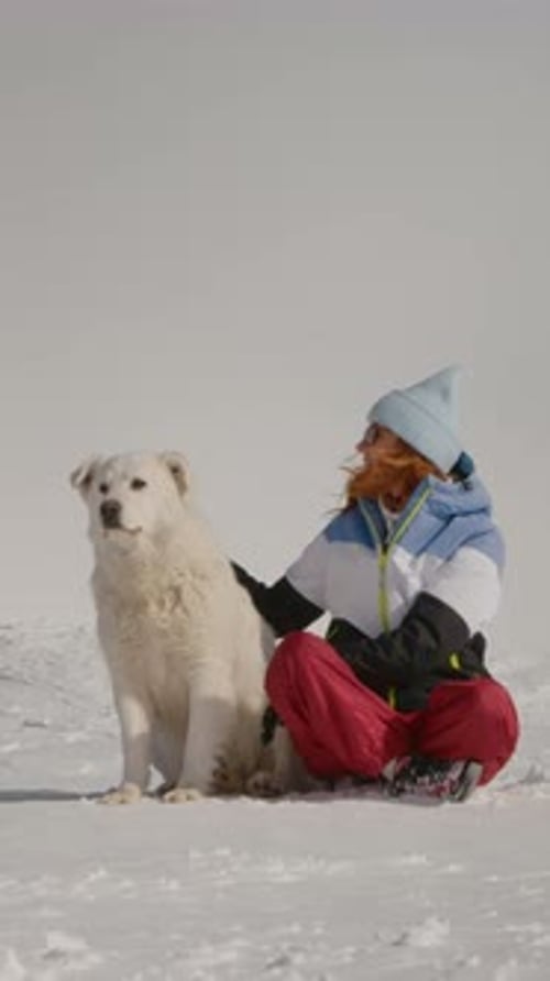 Woman Pets Her White Dog in the Snow