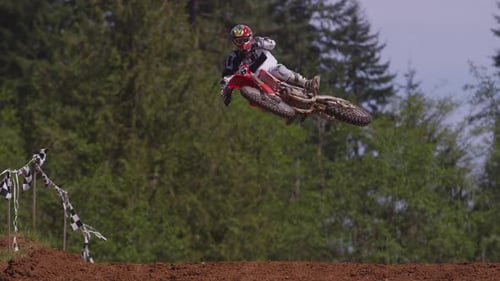 Motocross rider jumping over hill in slow motion