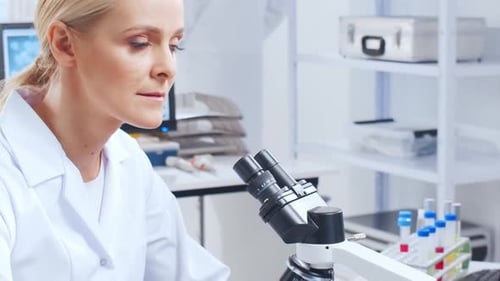 Female Scientist Using Microscope in Bright Lab