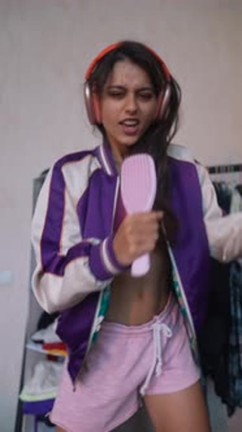 With Enthusiasm the Youthful Girl is Performing a Song Into a Hairbrush Mimicking a Microphone