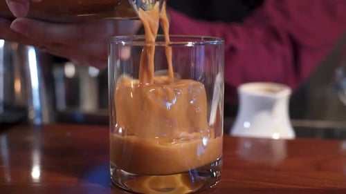 Bartender pouring coffee chocolate cocktail over ice in glass, slider close up slow motion 4K