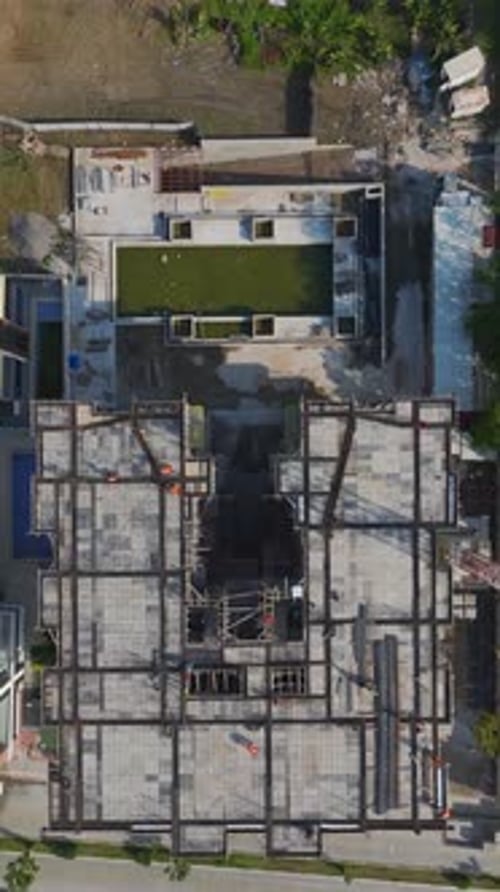 Vídeo vertical Los trabajadores colaboran en la construcción de paredes utilizando mezcladoras de concreto, metal y herramientas en un