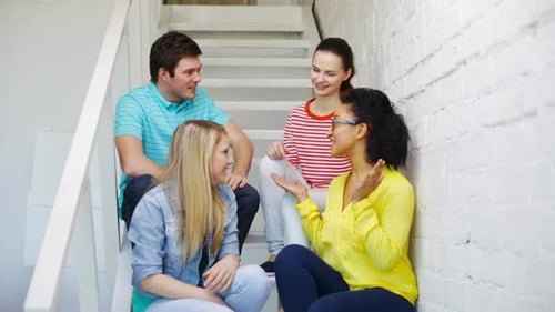 Four friends sitting together on stairs high five
