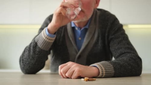 Senior Man Takes Pills with Water in Home