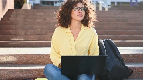 Using laptop. Beautiful woman student is near the university outdoors.