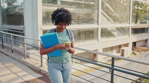 Smiling Student Walking on College Campus Using Phone