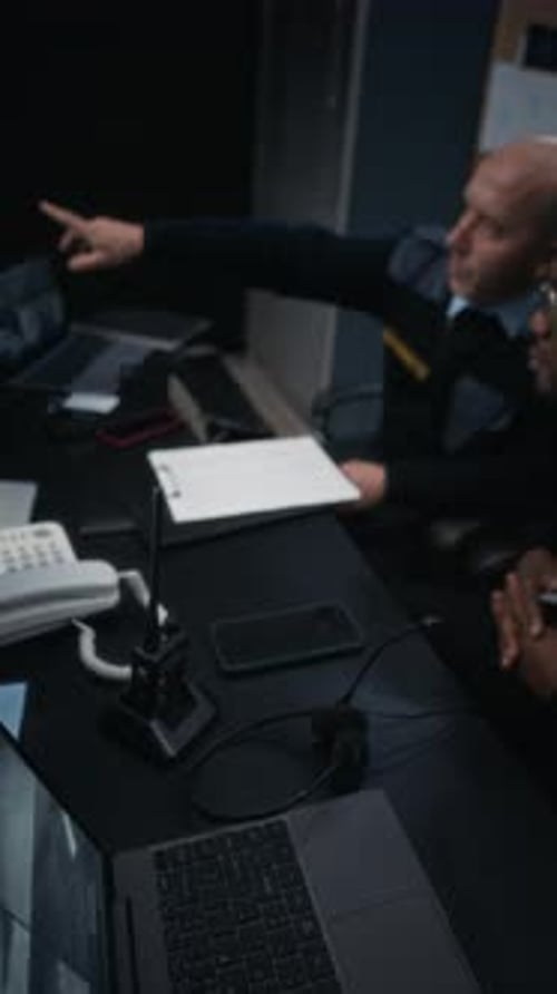 Two Security Guards Discussing Documents and Monitoring CCTV Cameras