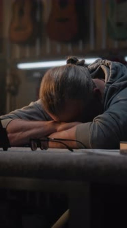 Erschöpfter Handwerker schaut sich das Metronom an und sitzt in einer stilvollen Werkstatt