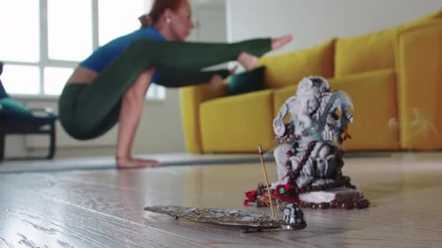 Femme faisant du yoga et fumant de l'encens au premier plan