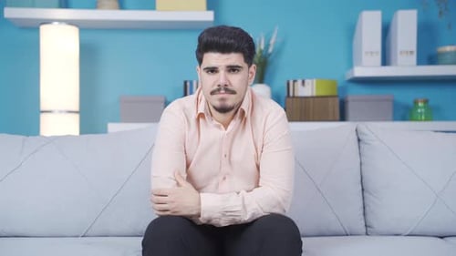 Pensive Man Sitting on Sofa at Home