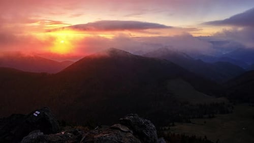 Nature Landscape with a Hazy Sunrise Over a Mountain Range with Cumulus Clouds Dotting the Sky