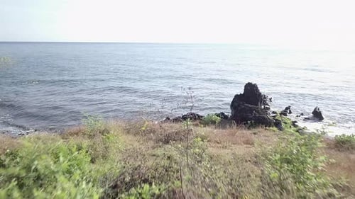 Luftaufnahme eines Vorwärtsflugs zum Strand, Sedimentfelsen und Wasserspritzen auf die Felsen in Bal