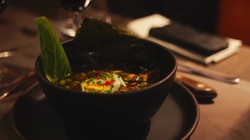 Asian Soup in Dark Restaurant with Garnishes