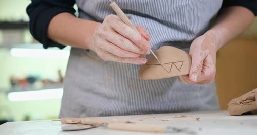 Woman Creates Pattern on a Clay Pot By Hands in Artistic Studio