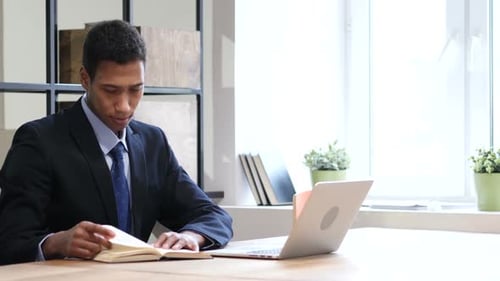Adult Man Reads and Writes at Desk