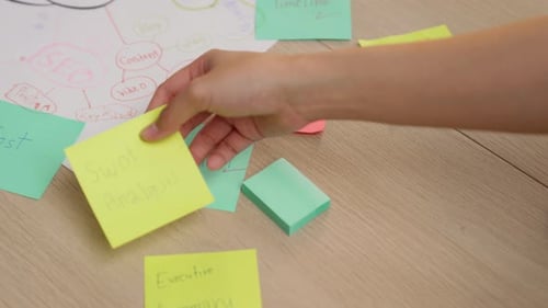 Successful female businesswoman hand writing marketing on paper. Variegated.