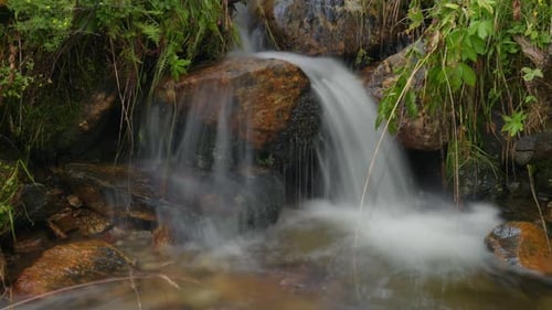 Timelapse of river flowing over time in to a small pond with a long exposure so the water looks