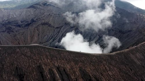 Active Mt Bromo Volcano, Aerial orbit shot as traveler hiking peak