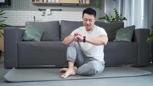 sporty man using fitness smart watch at home. Young male watching a smartwatch training data app