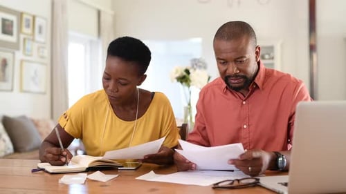 Couple Reviewing Documents Together at Home at Table