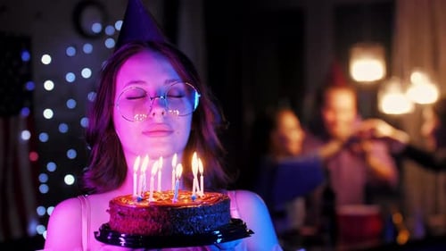 Woman Blowing Out Birthday Cake Candles at Party