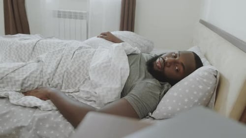 Man waking up in his bed in the morning