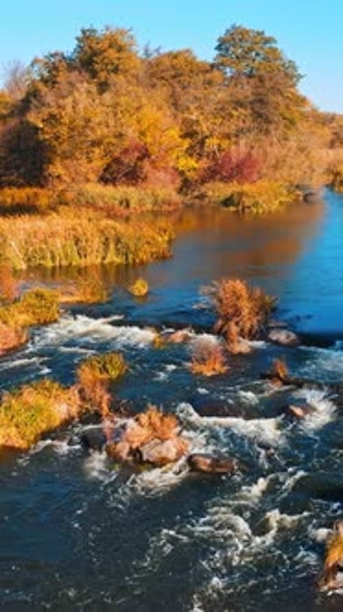 Aerial view. Flying over the beautiful autumn river. Beautiful blue sky over the water.