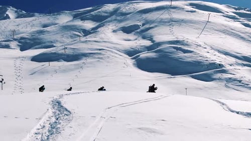 Drone moving over snowboarders walking in the mountains. Aerial shot of freeriders walking in snow.